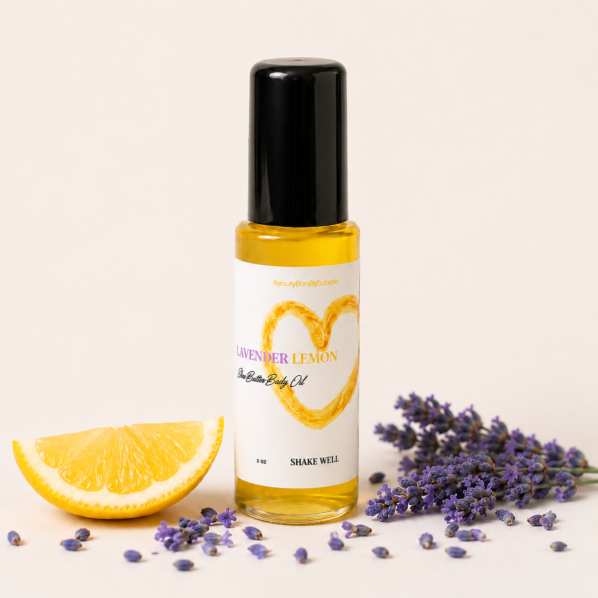 A bottle of Lavender Lemon essential oil with a black cap and white label, styled with a lemon slice, lavender sprigs, and scattered lavender buds on a light beige background.