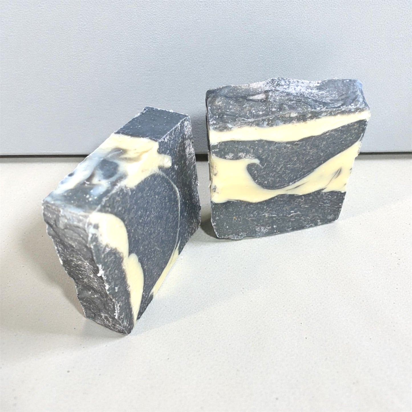 Two bars of soap with a black and white marbled pattern on a light gray background