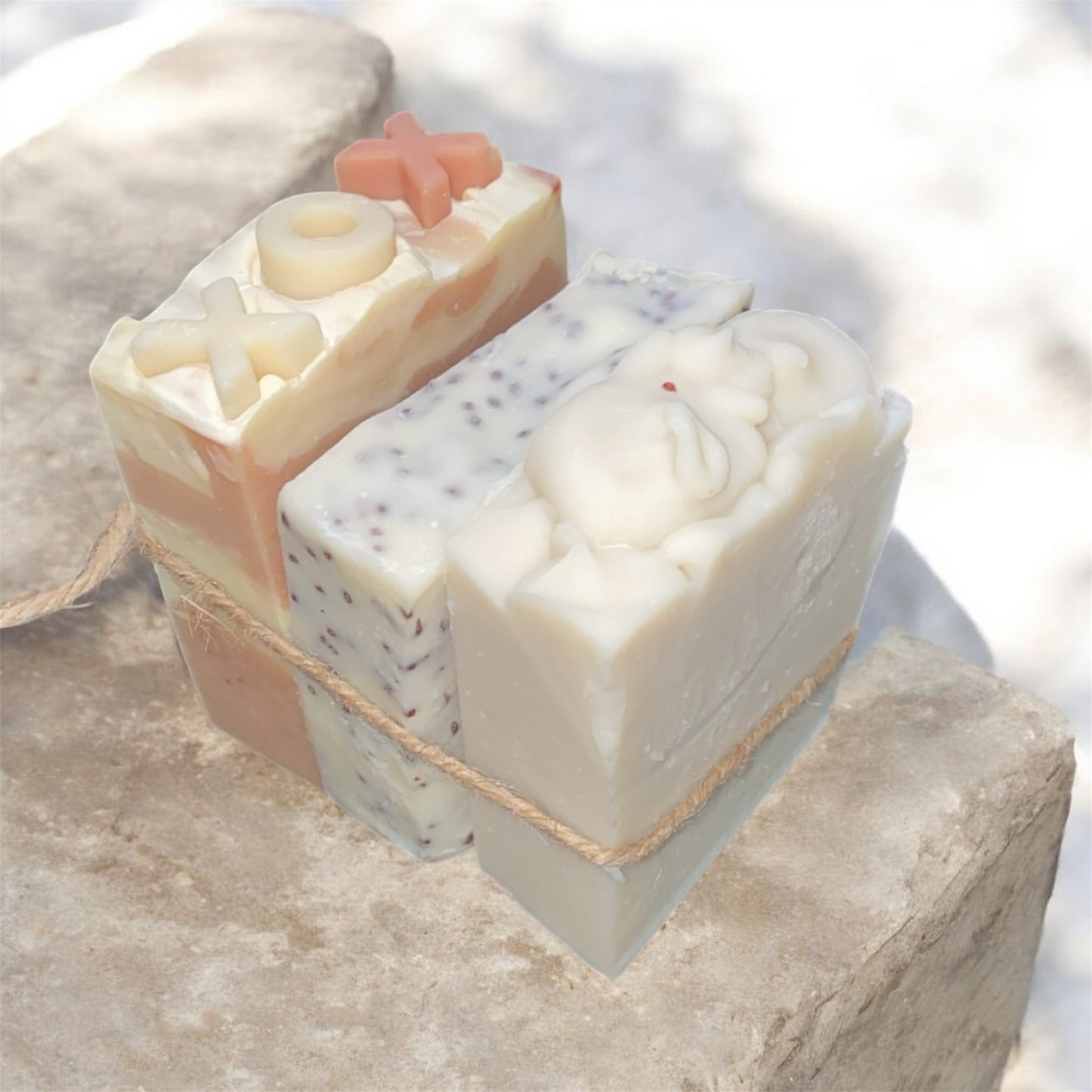 Three bars of soap with different textures and colors on a stone surface