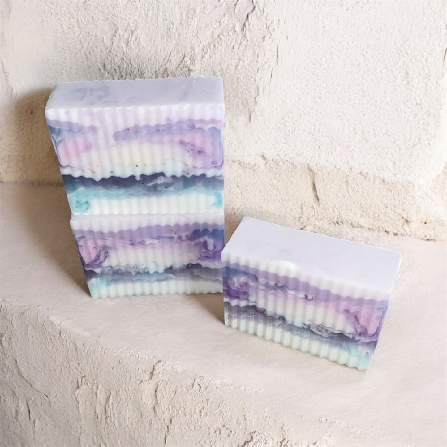 Stack of multicolored soap bars on a textured surface