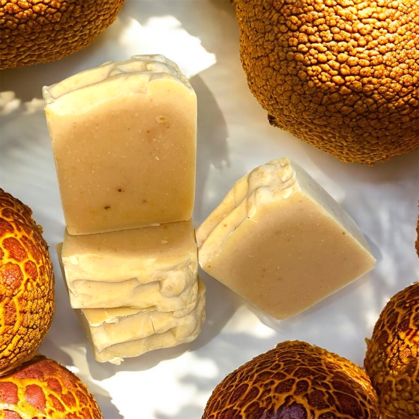 Three bars of soap on a white surface with textured orange stones around them.