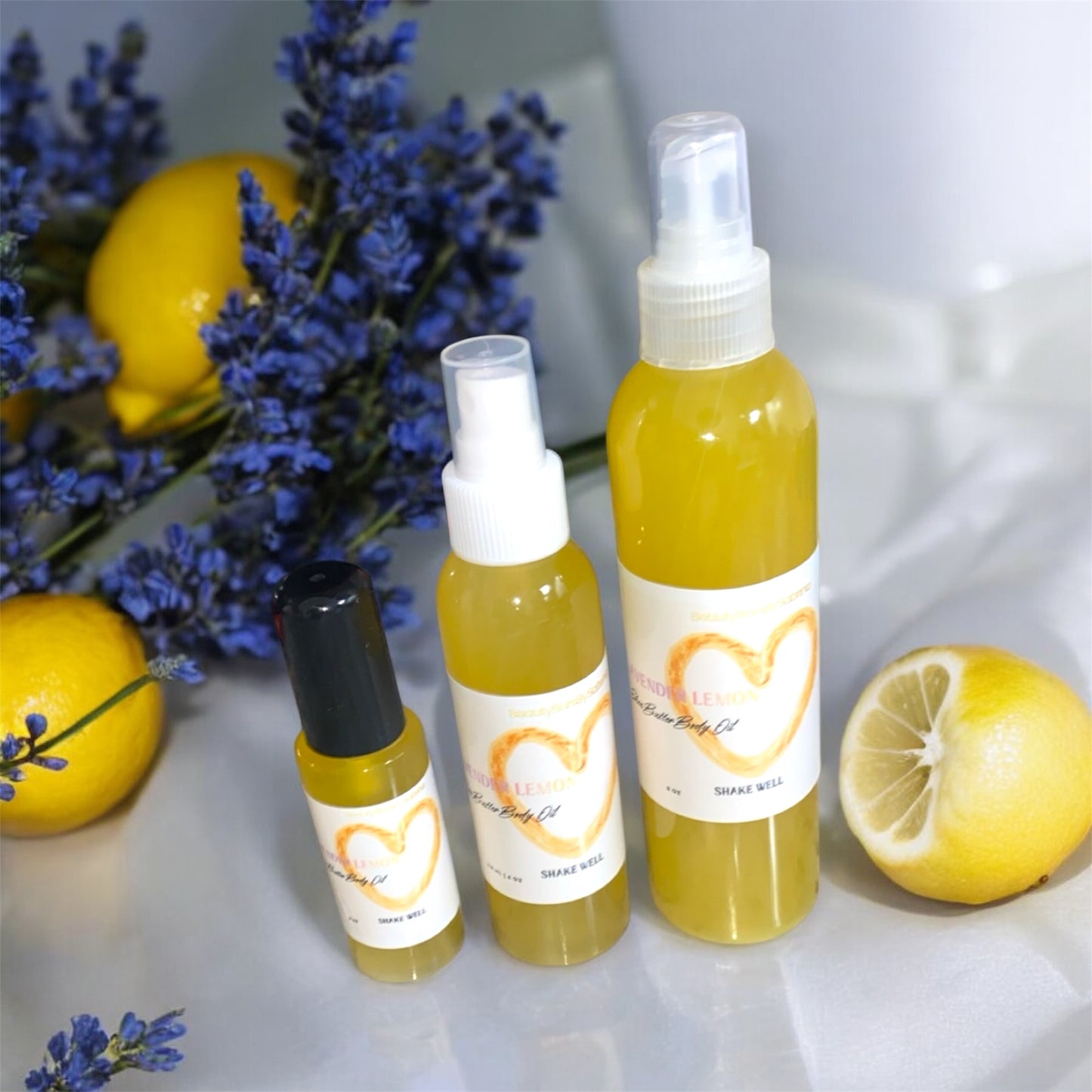 Three bottles of lemon body oil with lavender and lemons on a white background