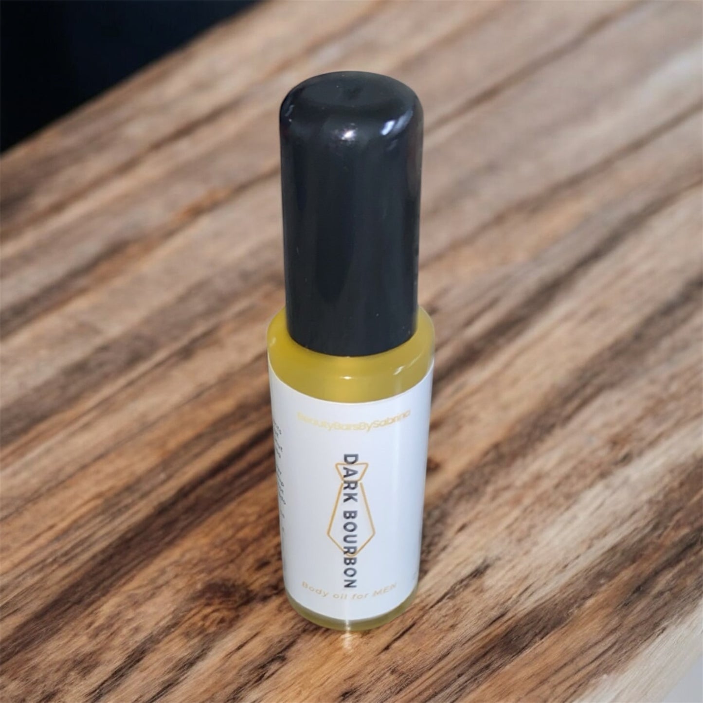 Small bottle labeled 'Dark Bourbon' body oil on a wooden surface