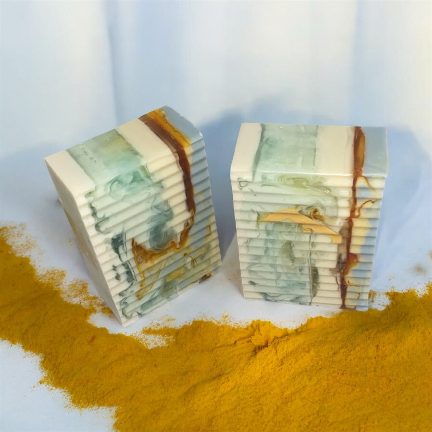Two rectangular blocks with marbled design on a white surface with yellow powder.