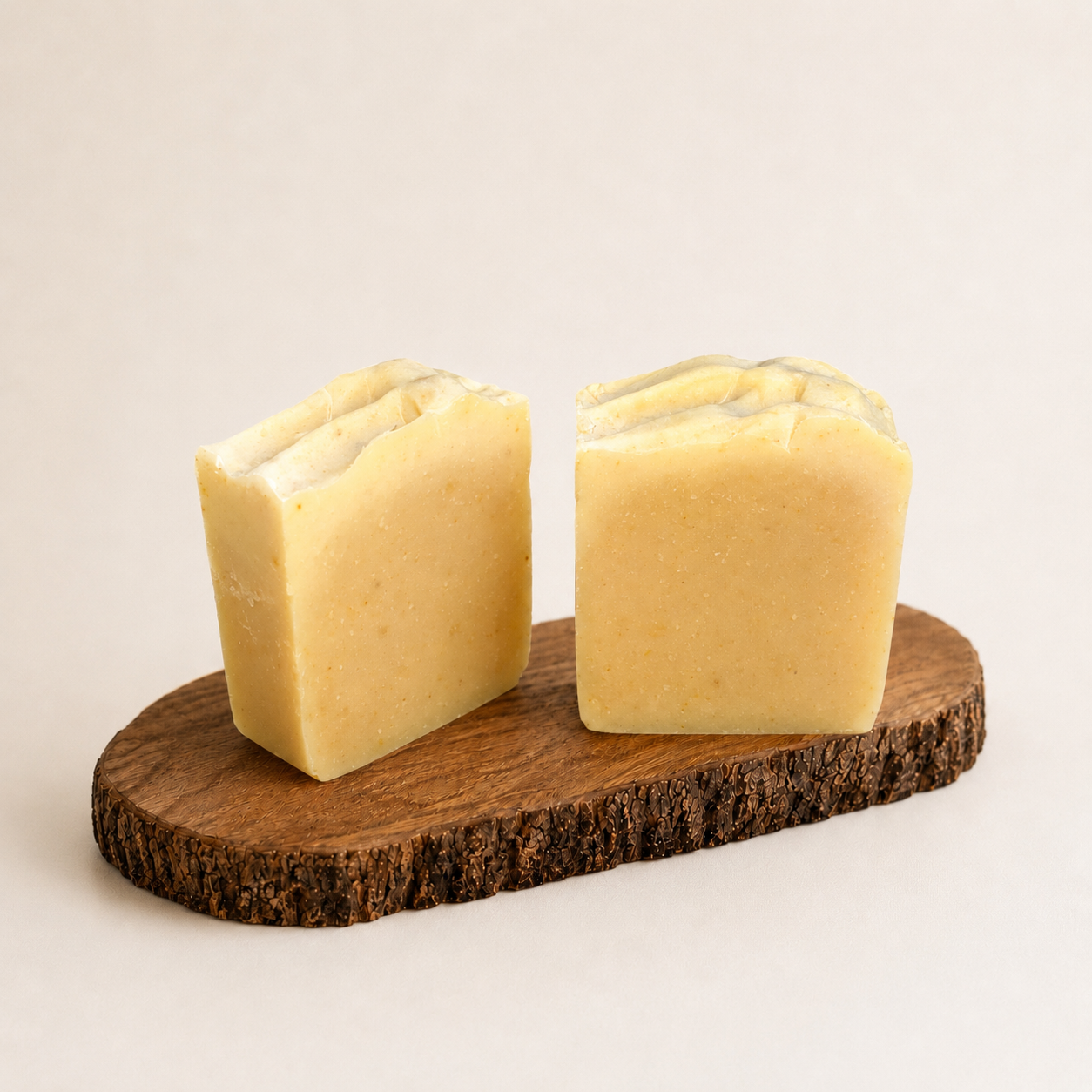 Two square-shaped soaps on a wooden stand with a plain background