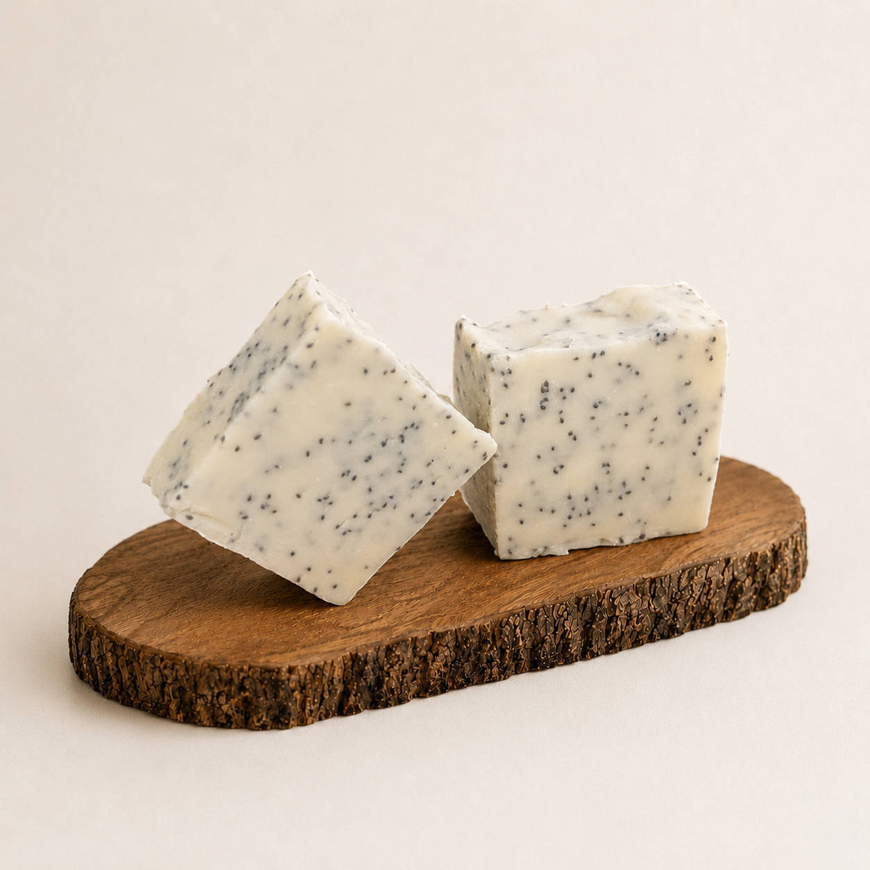 Two square-shaped soaps with cranberry seeds specks on a wooden board against a light background