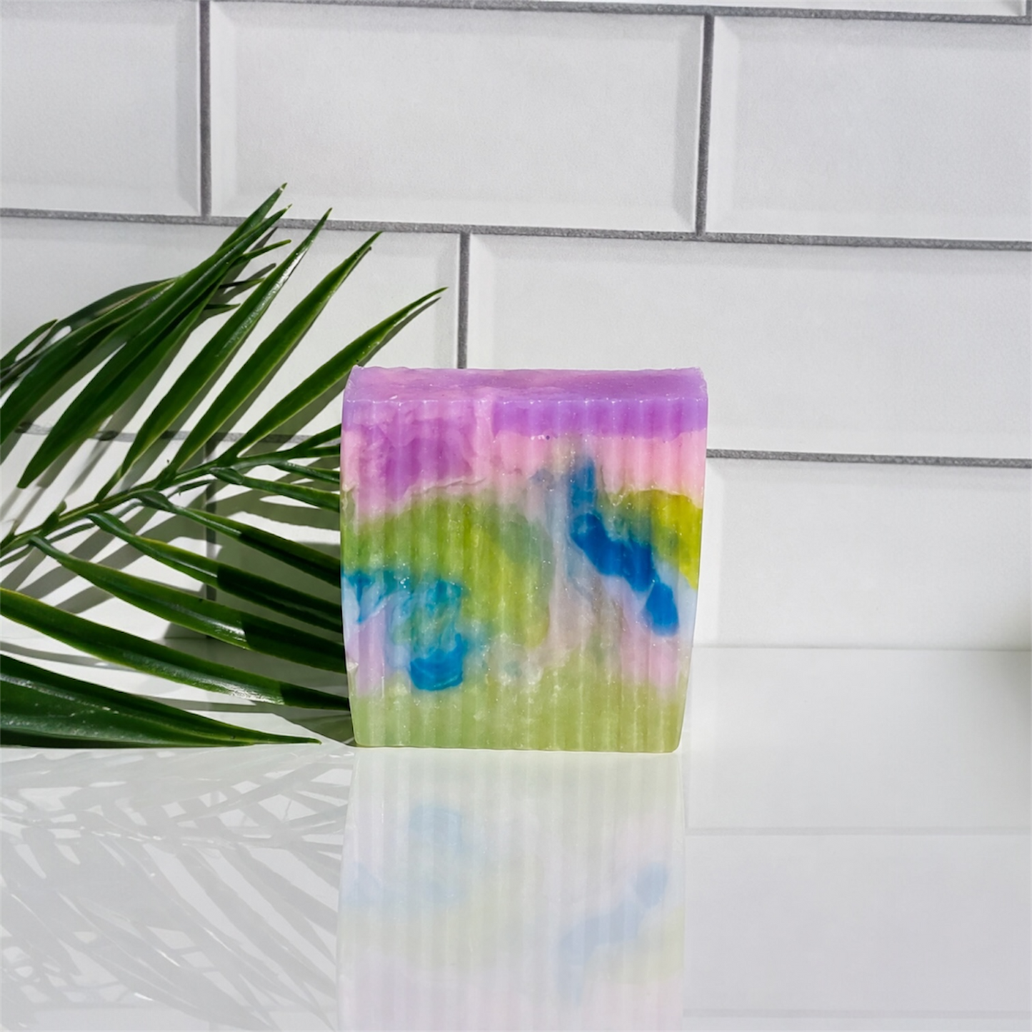 Colorful soap bar with a tie-dye pattern on a white tiled background