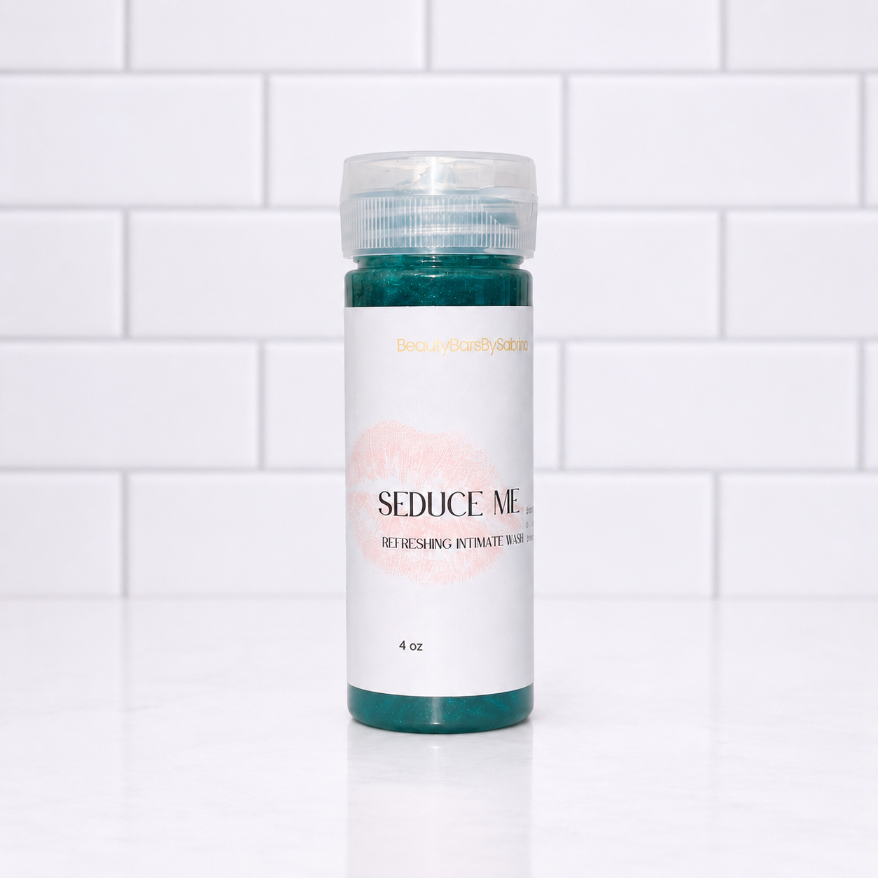 A 4 oz bottle of Seduce Me Refreshing Wash, featuring a white label with a pink lip print and teal product visible at the top and bottom, set against a white subway tile background.