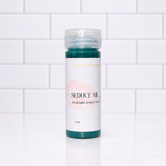 A 4 oz bottle of Seduce Me Refreshing Wash, featuring a white label with a pink lip print and teal product visible at the top and bottom, set against a white subway tile background.