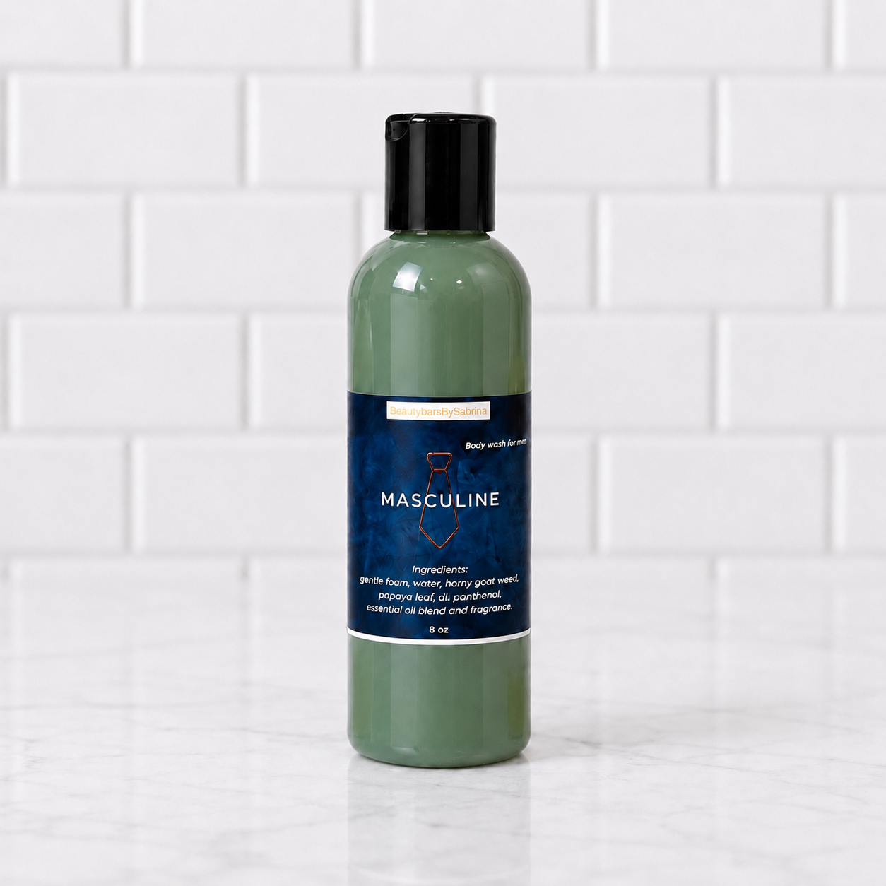 A 8 oz bottle of Masculine body wash with a black cap and a dark blue label, set on a white marble surface against a white subway tile background.