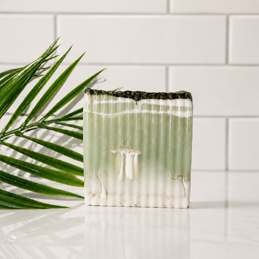 Close-up of a  soap with a grid pattern with white background and green leaf.