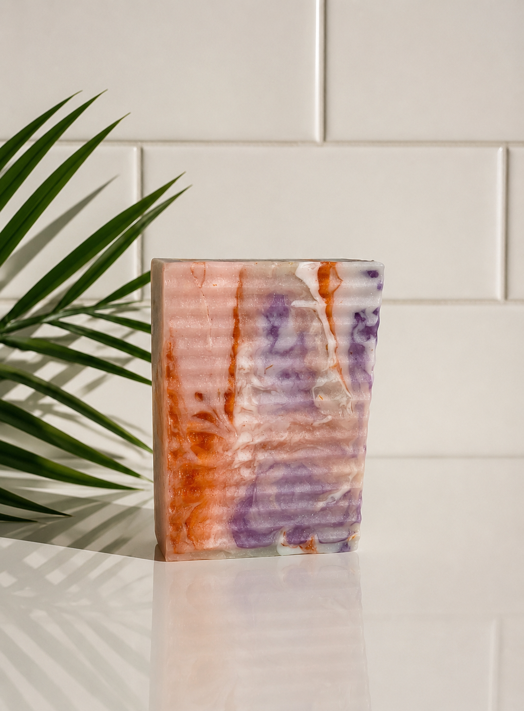 Colorful soap with abstract design on a white surface with a plant in the background