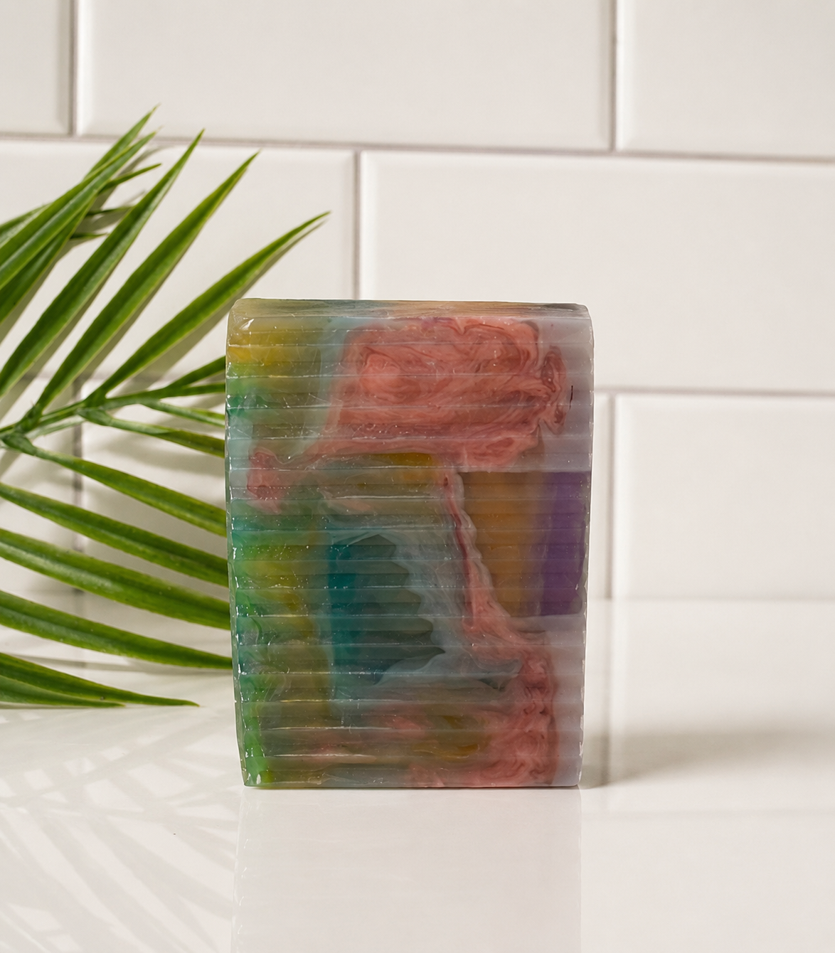 Colorful soap bar with a textured surface on a white surface with a plant in the background
