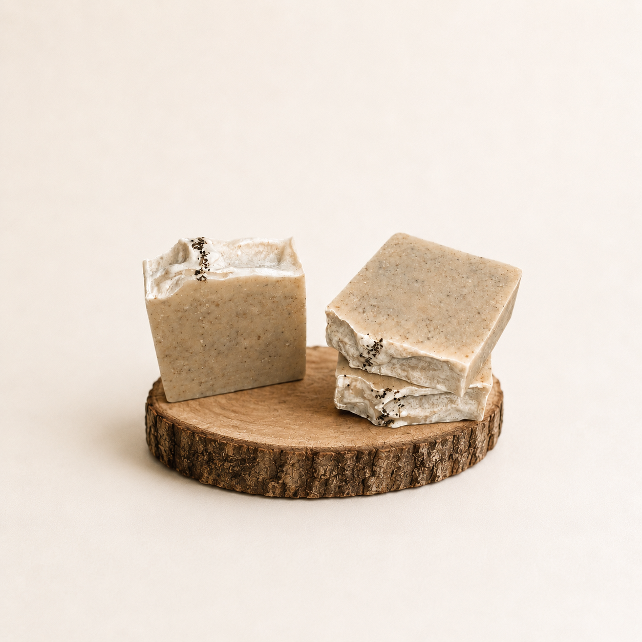 Three bars of soap on a wooden stand with a plain background