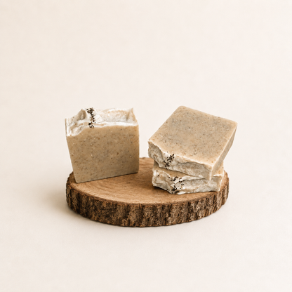 Three bars of soap on a wooden stand with a plain background