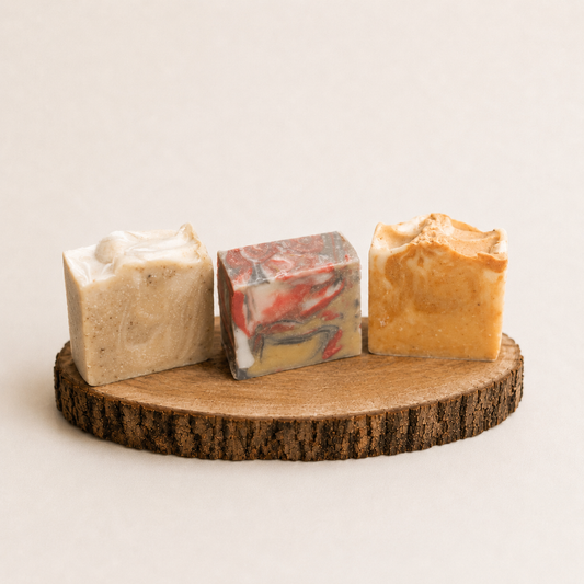 Three different colored soap bars on a wooden stand with a plain background