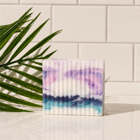 Colorful soap bar with a palm leaf on a white tiled background