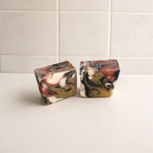 Two marbled soap bars on a white surface with tiled wall background