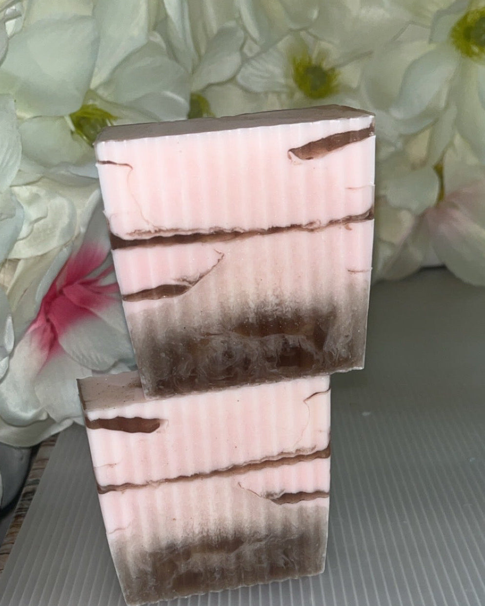 2 pink and brown soaps stacked with flower background 
