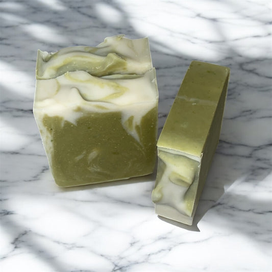 Two bars of green soap with white swirls on a marble surface