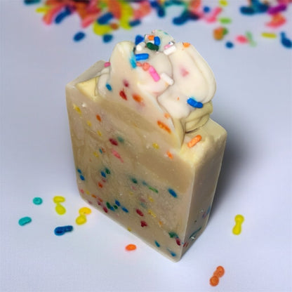Square block of soap with colorful sprinkles on top, against a light background.