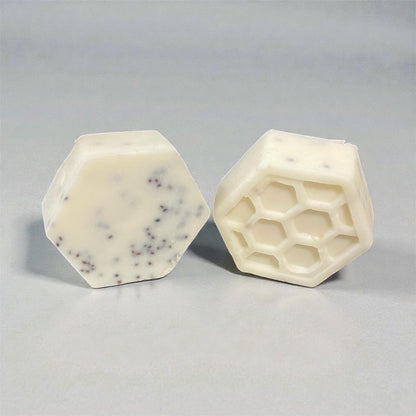 Two hexagonal soap bars with a honeycomb pattern , cranberry seed infused with a gray background