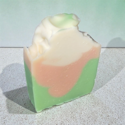 Colorful soap bar with green and pink layers on a textured surface