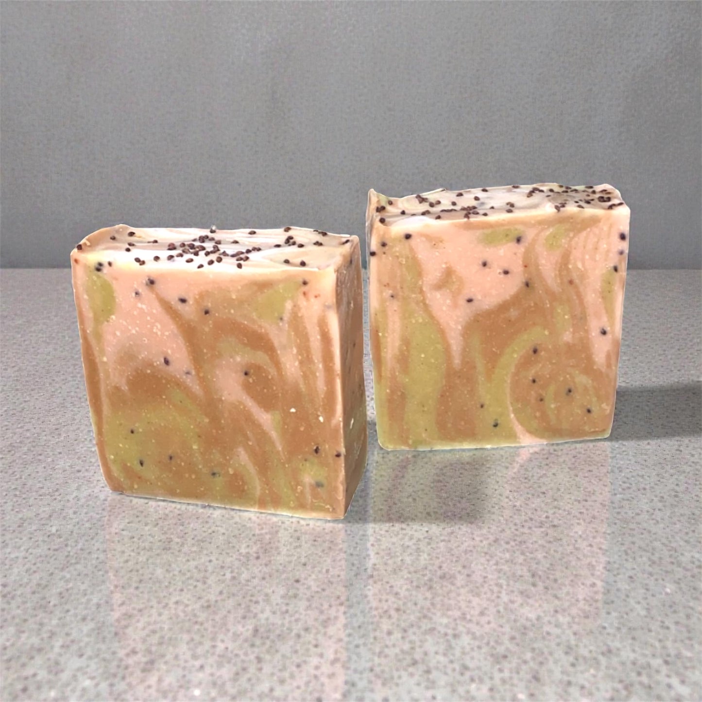 Two square soap bars with marbled pattern on a gray surface