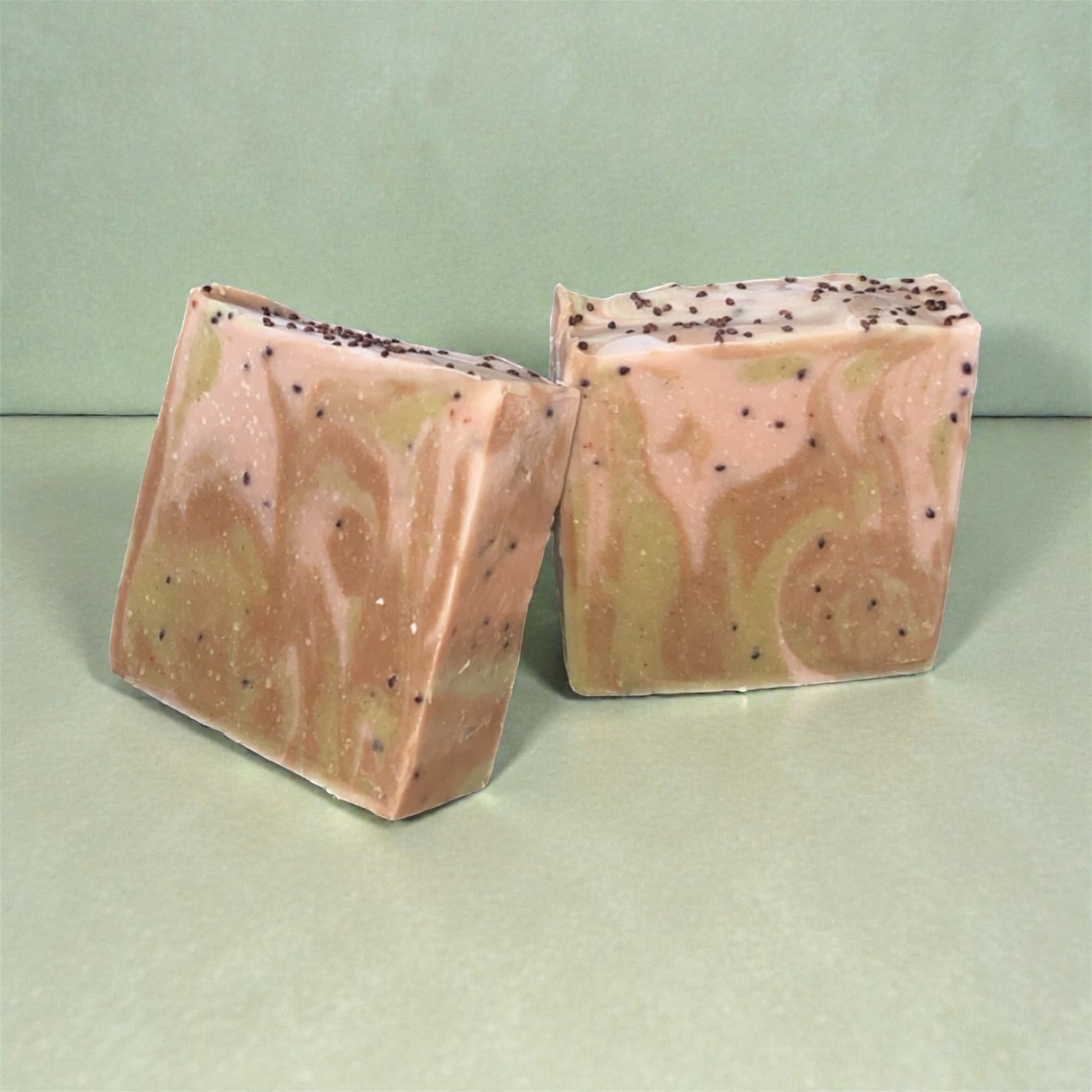 Two pink and green marbled soap bars on a light green background