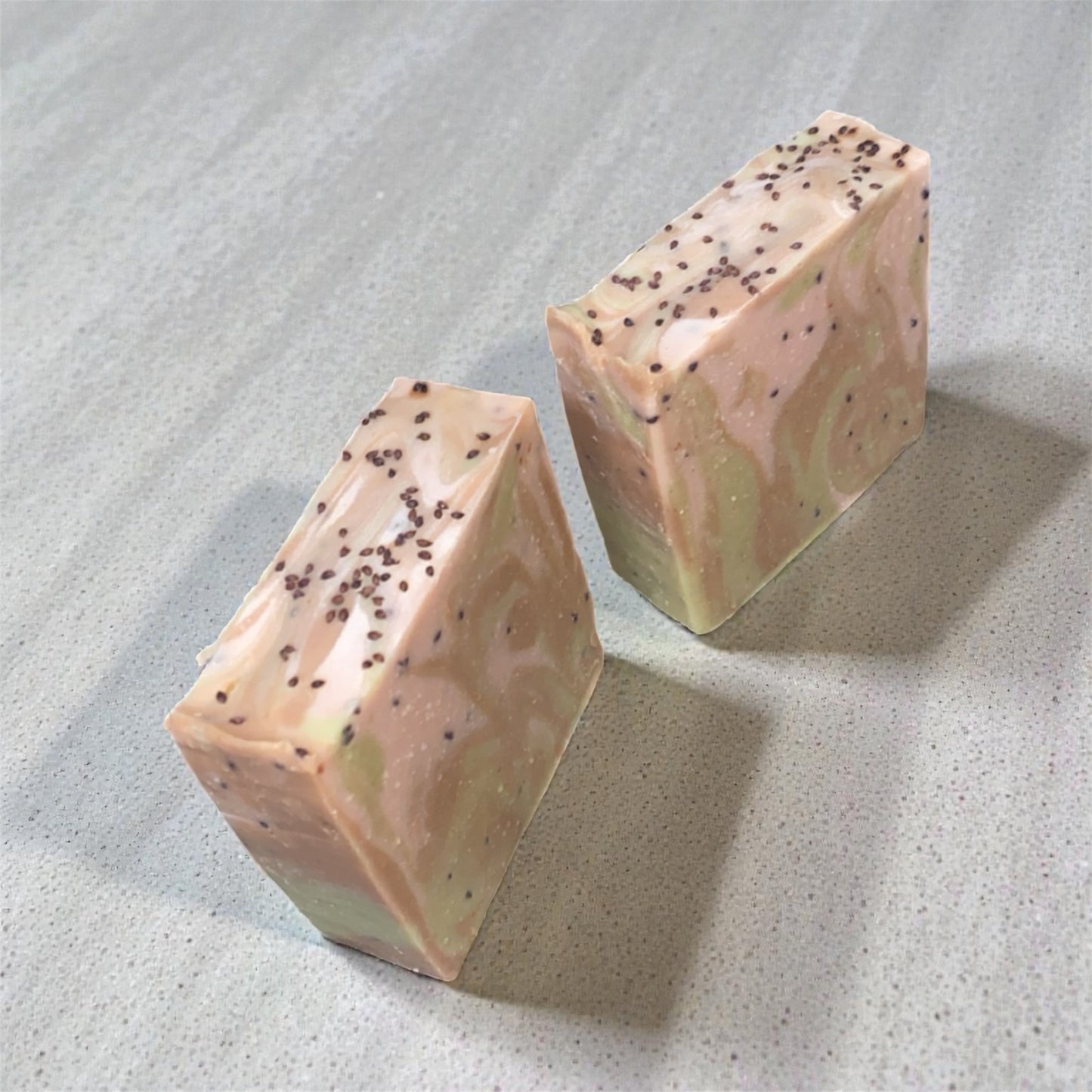 Two geometrically shaped soap bars with speckled texture on a textured surface