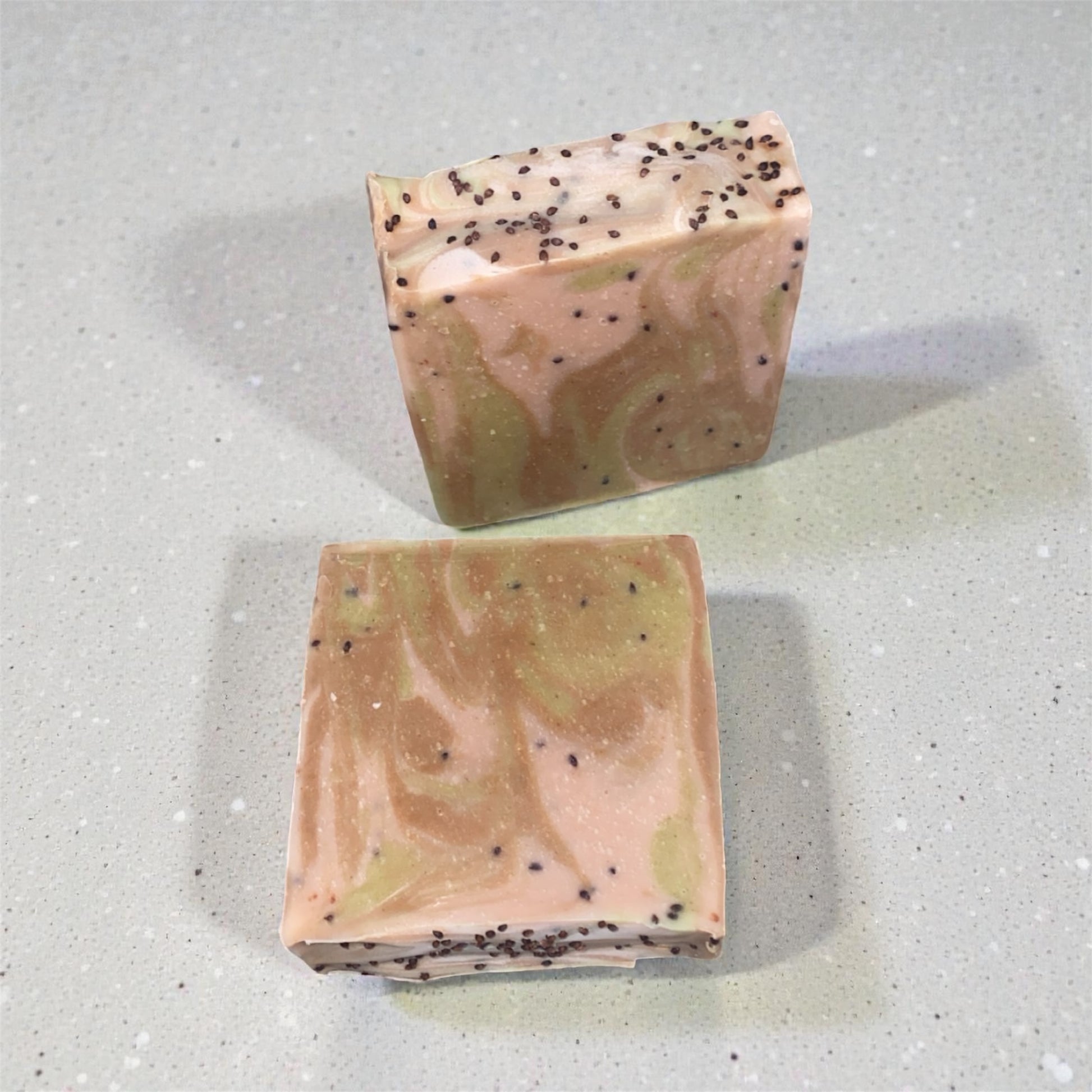 Two bars of soap with a marbled pattern on a textured gray surface