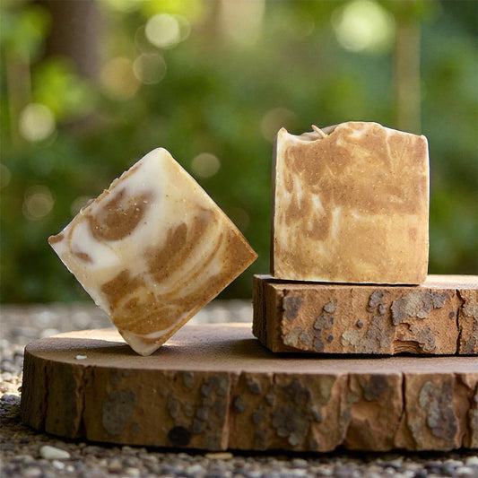 Two soap bars with a marbled pattern on a wooden block against a natural background.