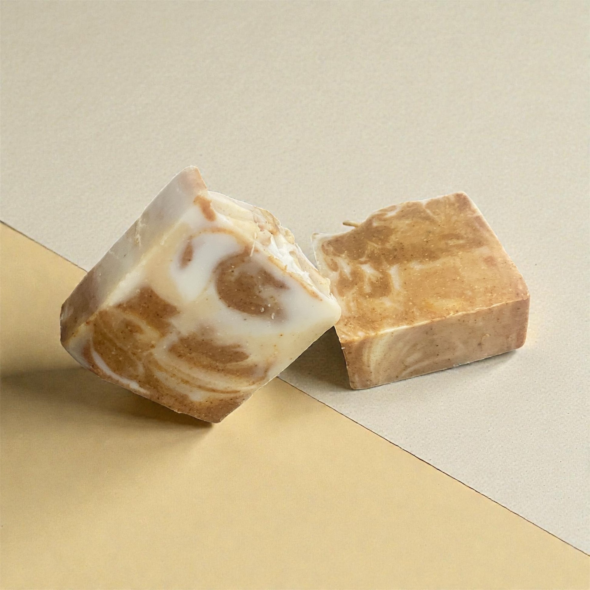 Two pieces of soap with a marbled pattern on a beige background