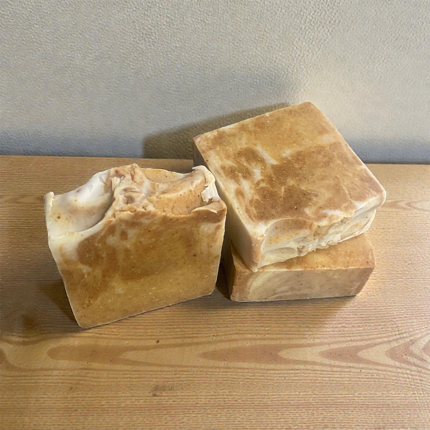 Three bars of brown soap on a wooden surface with a neutral background