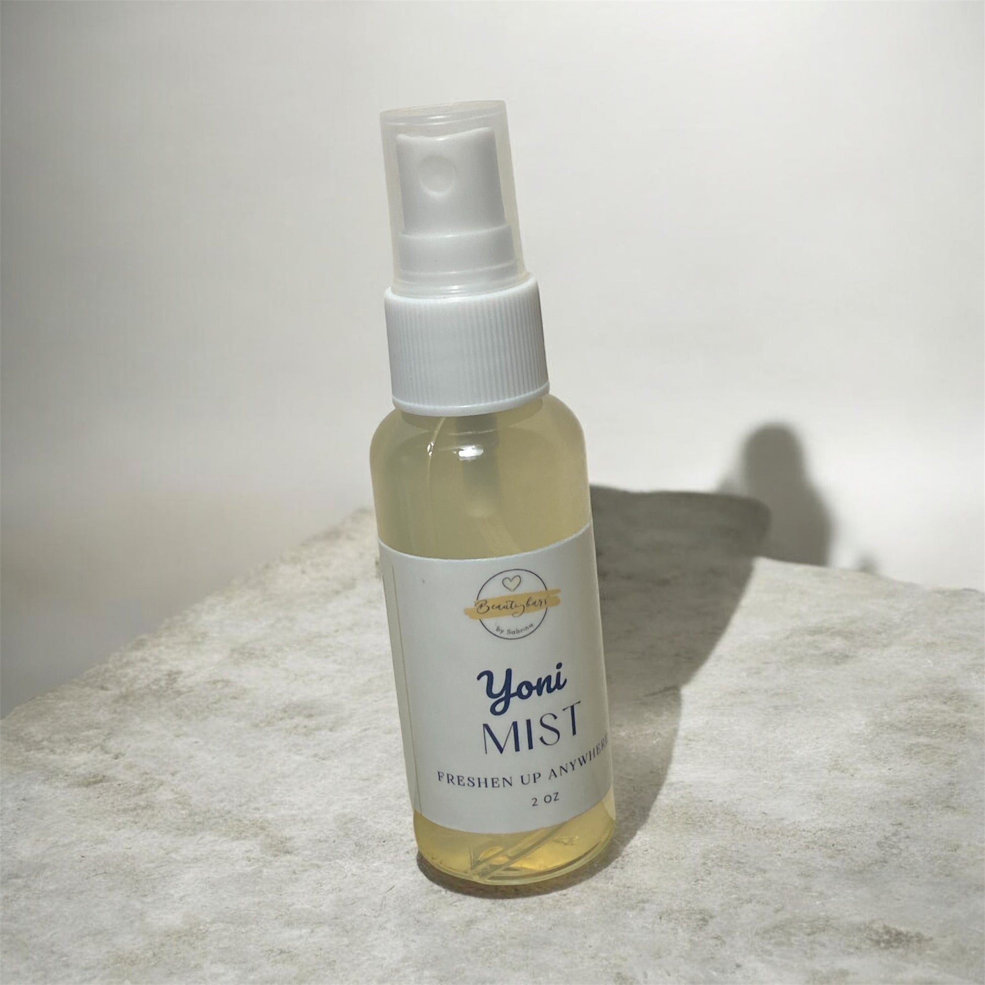 Bottle of Yoni Mist on a textured surface with a white background