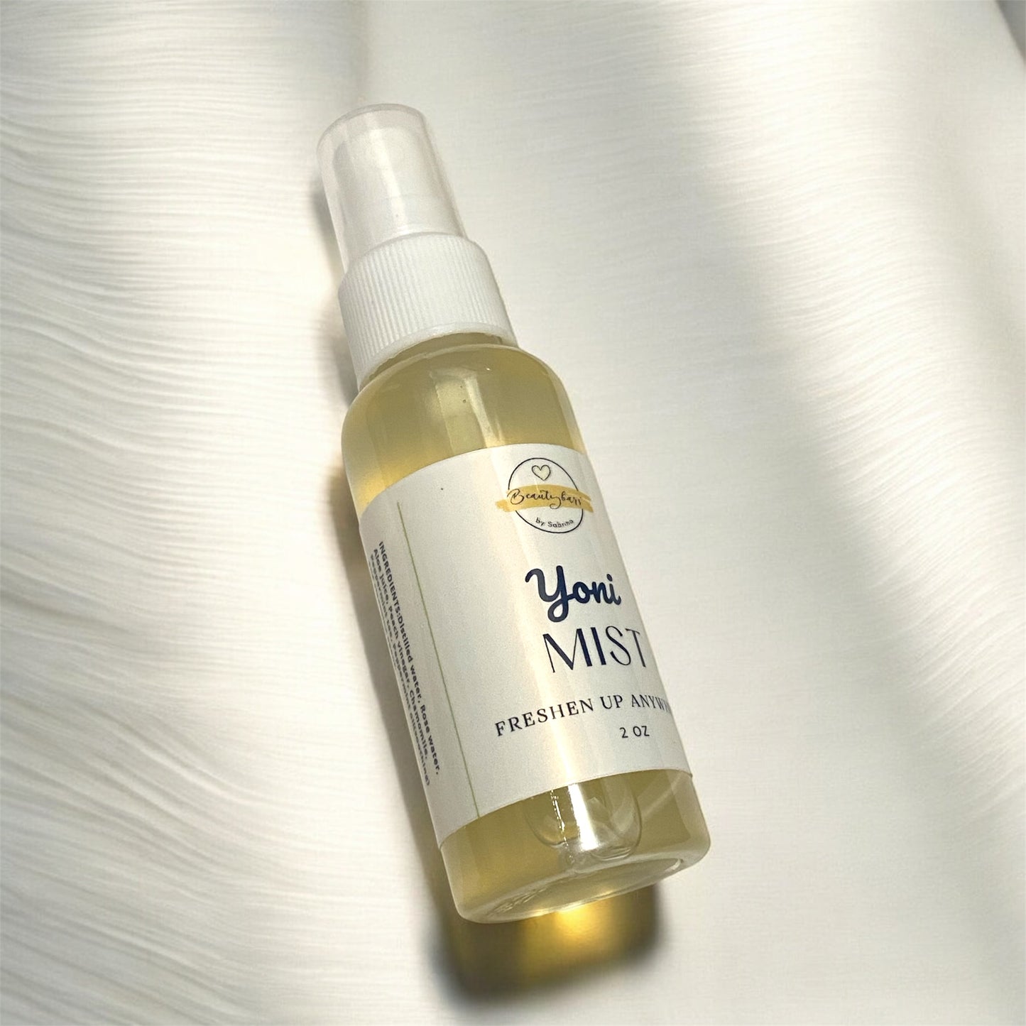 Bottle of Yoni Mist on a textured white background