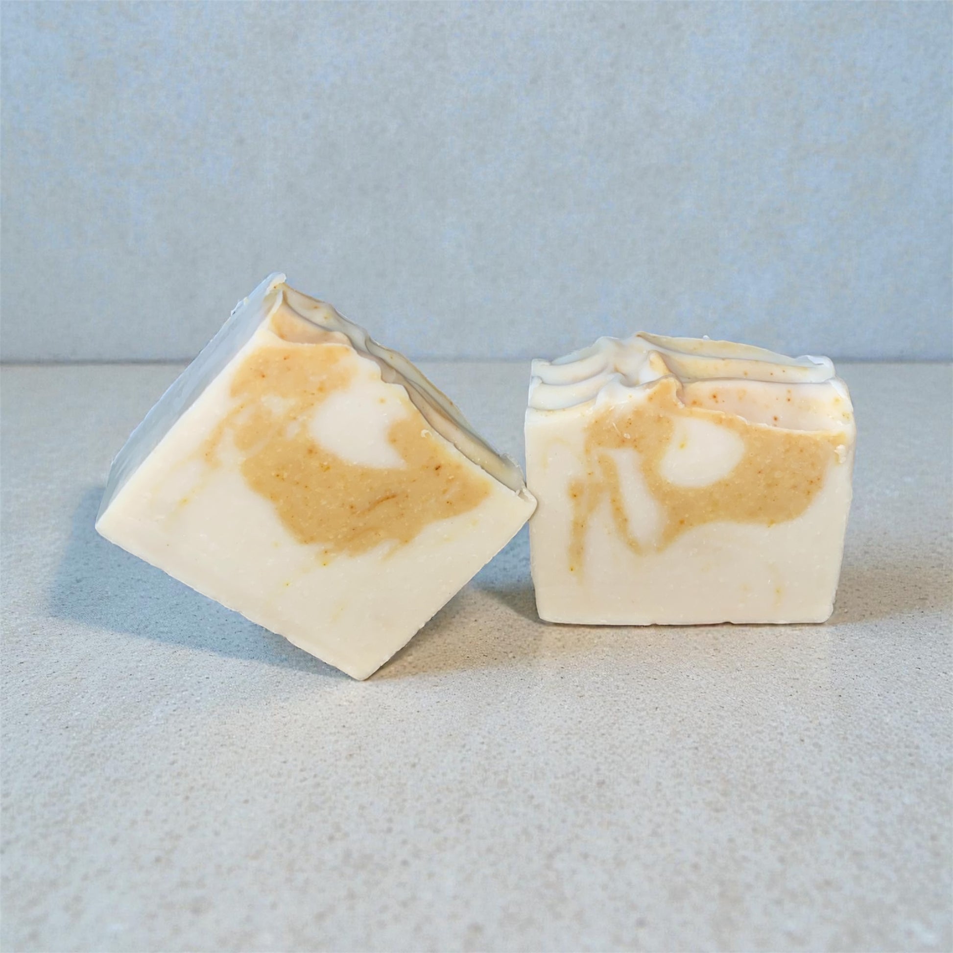 Two square bars of soap with a marbled pattern on a light blue background