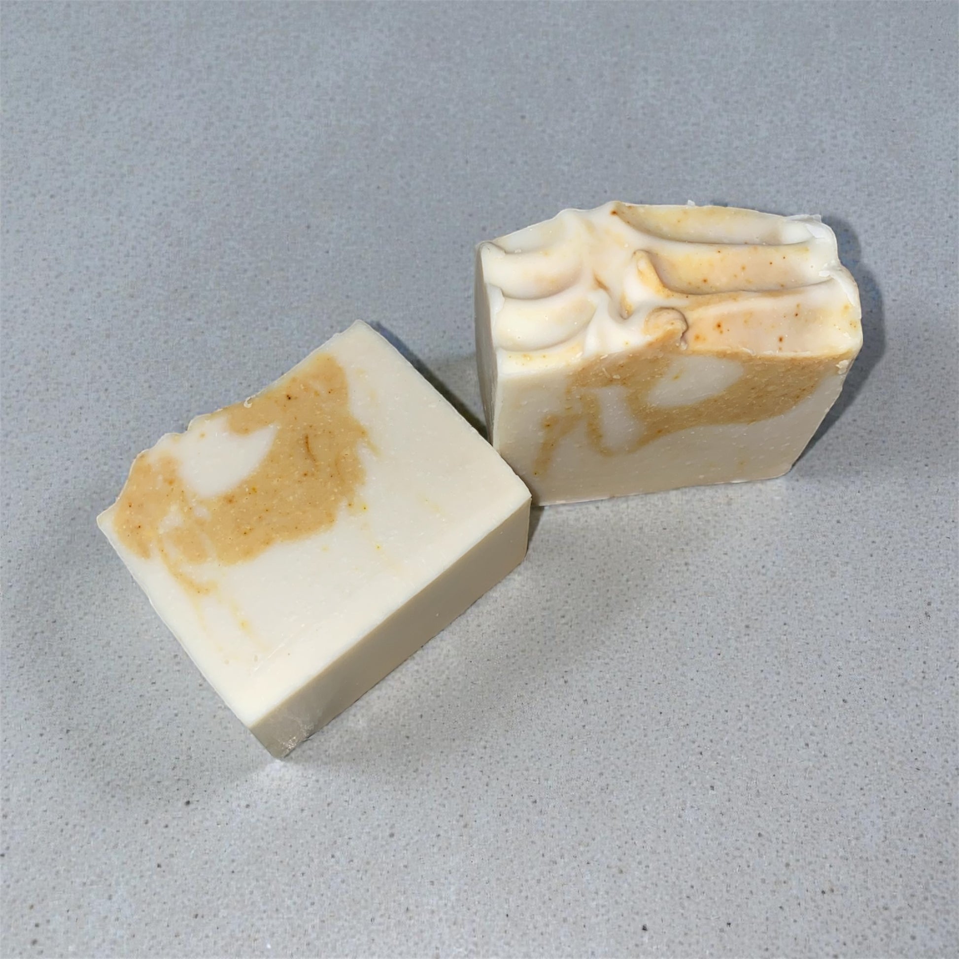 Two bars of soap with a marbled pattern on a gray surface