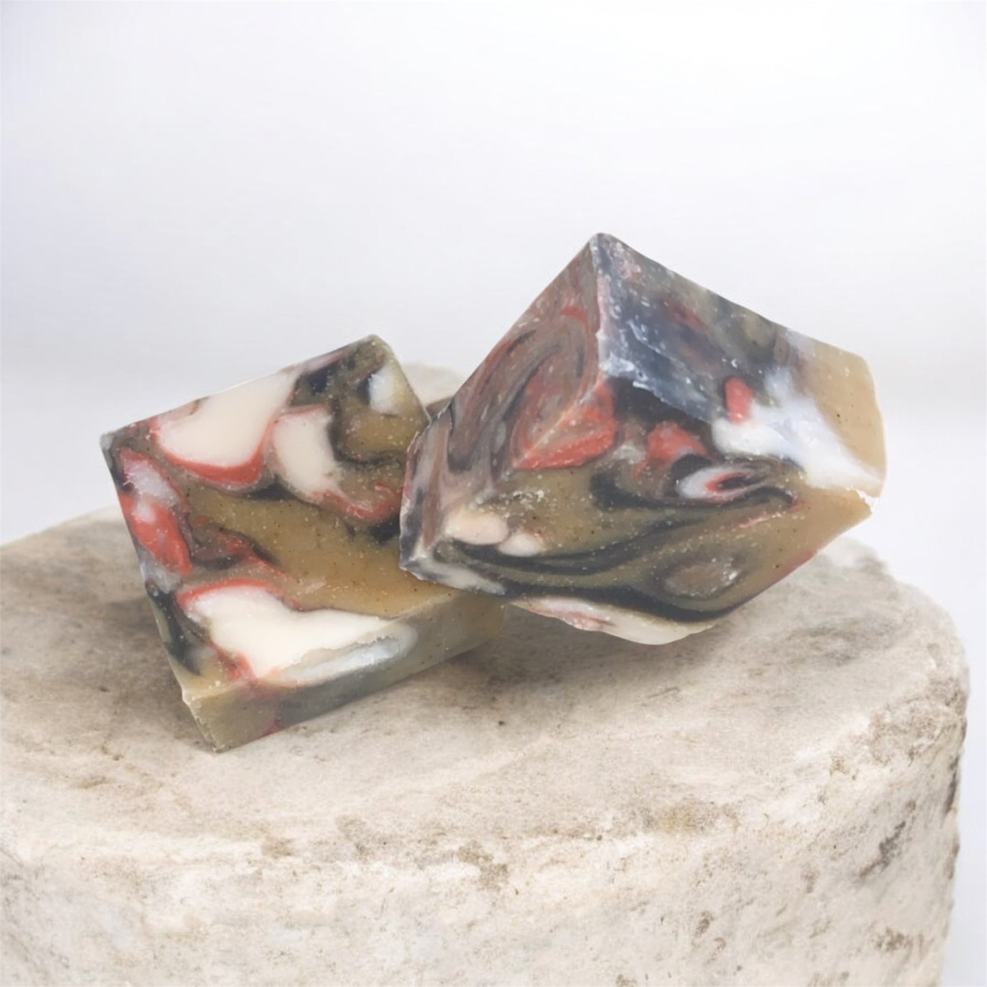 2 marbled colored soaps on a stone.