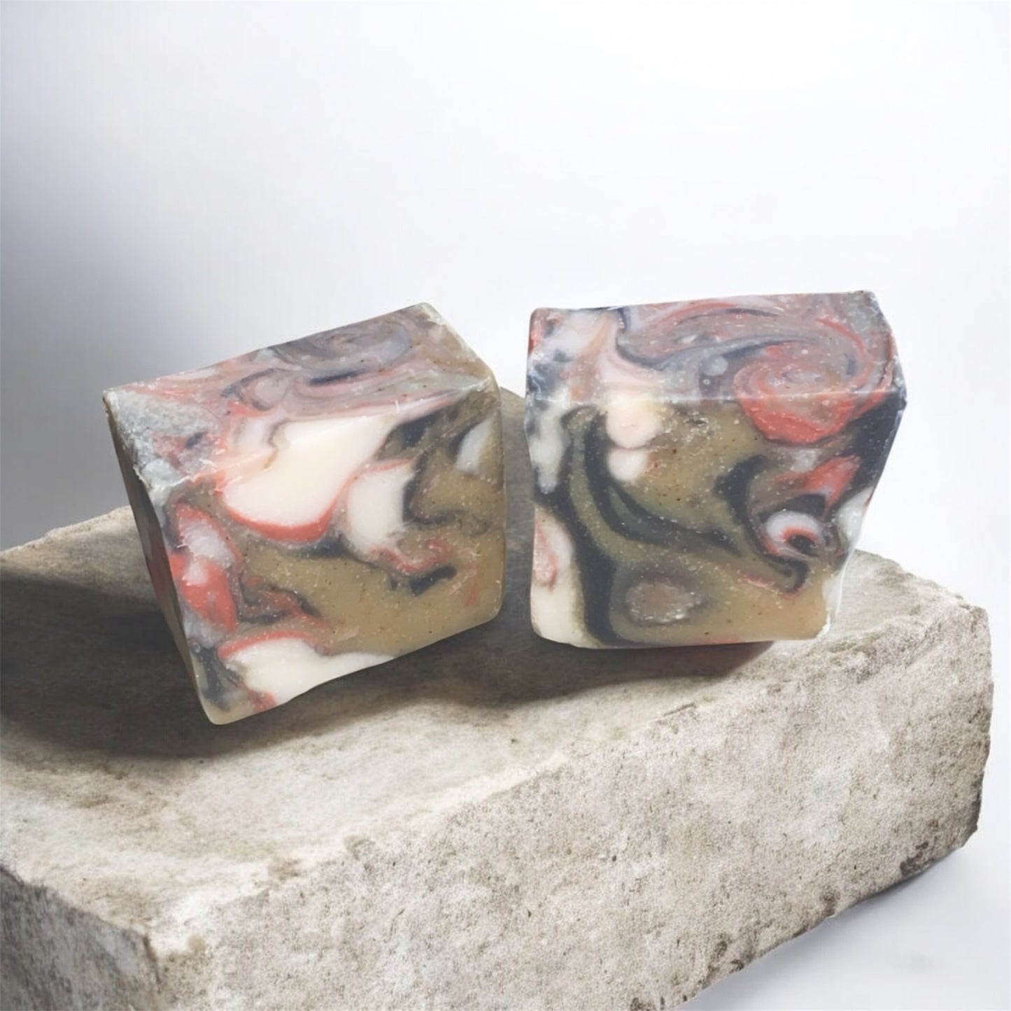 Two marbled soap bars on a stone surface with a white background