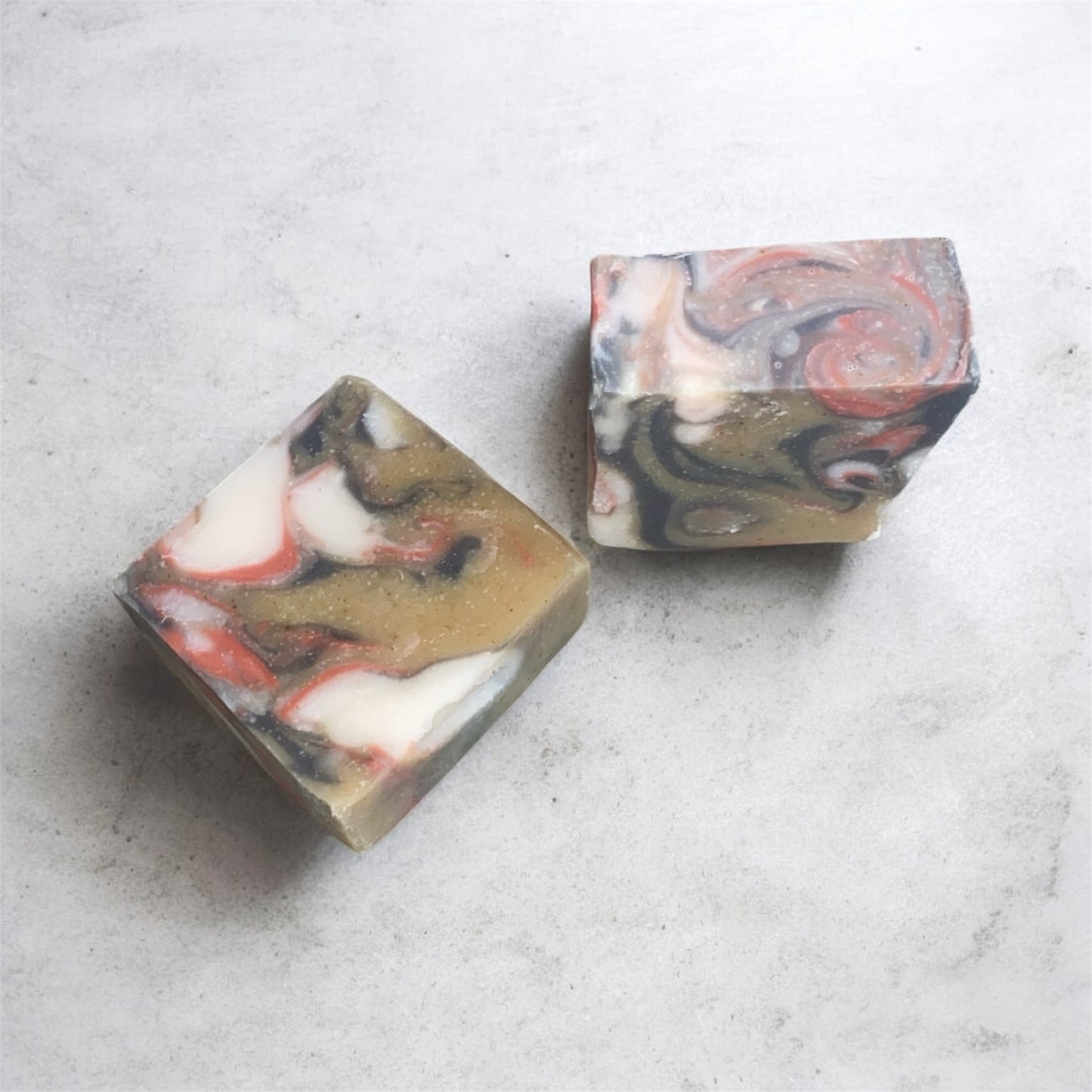 Two marbled soap bars on a light gray surface