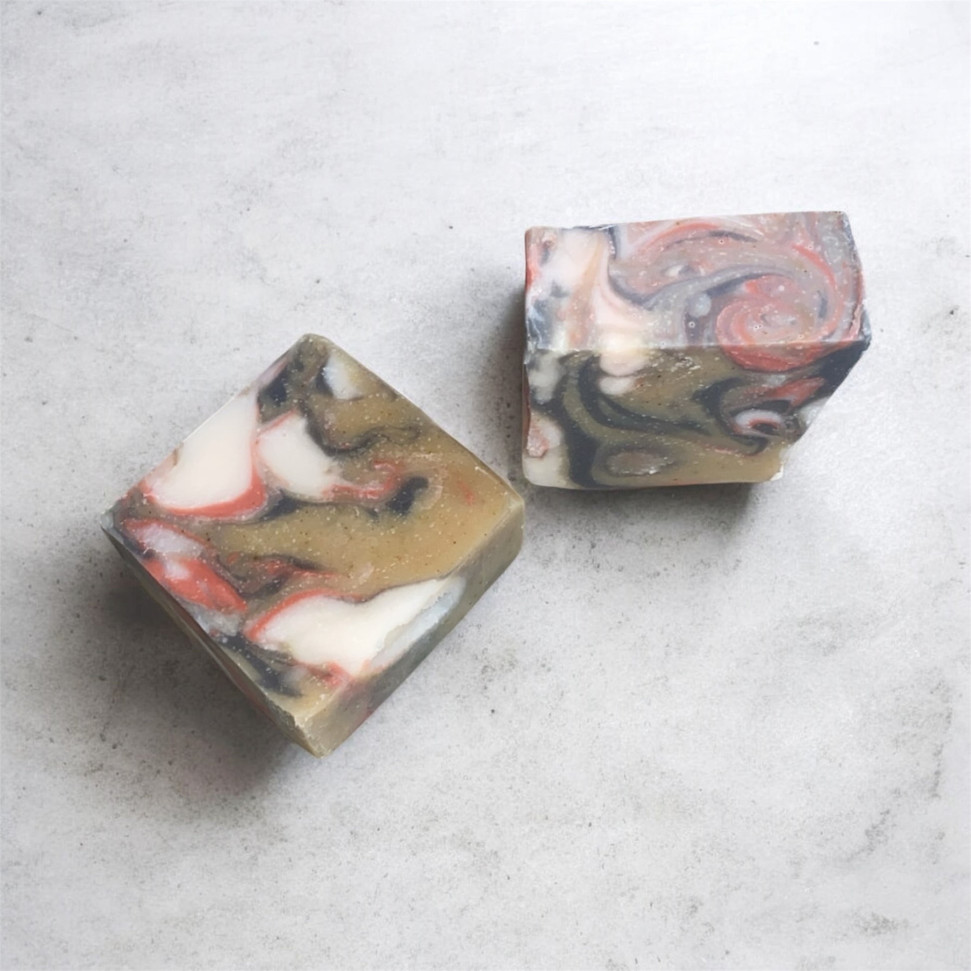 Two marbled soap bars on a light gray surface