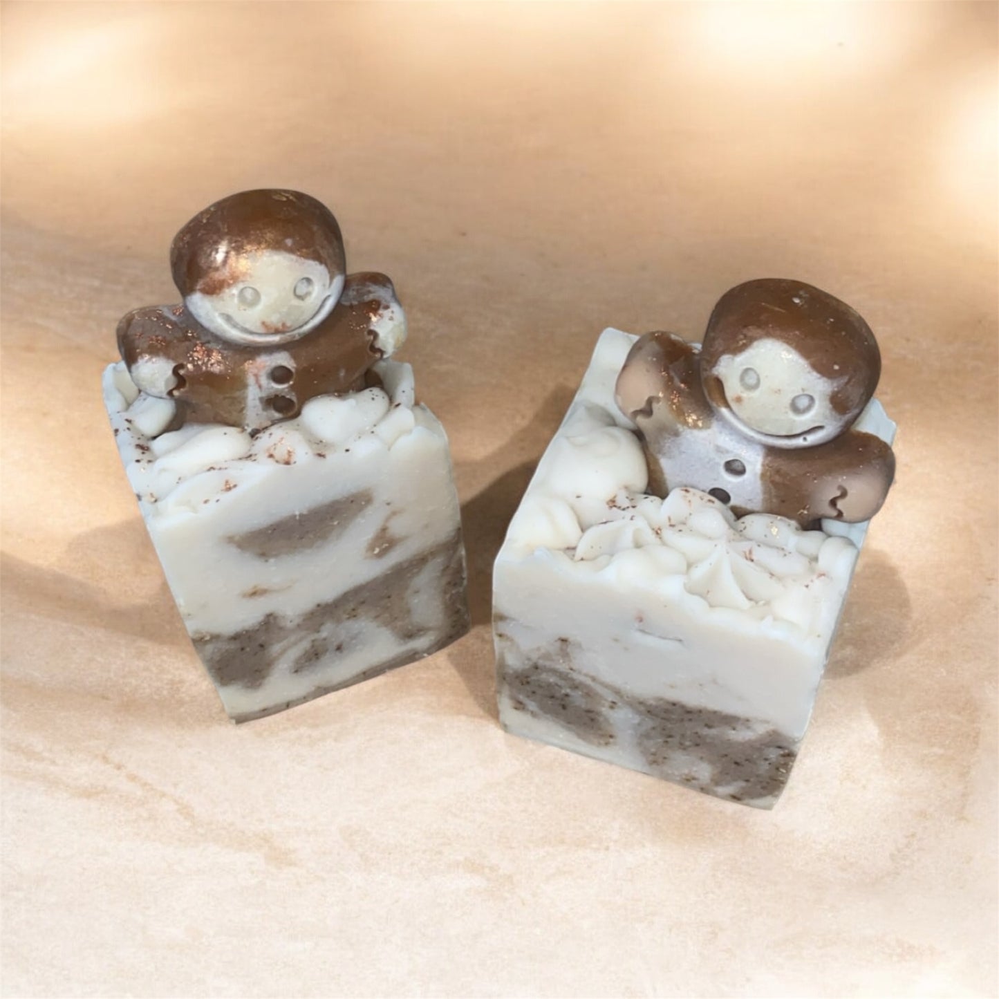 Two small soap with a gingerbread man figures on top with marbled design on a beige background