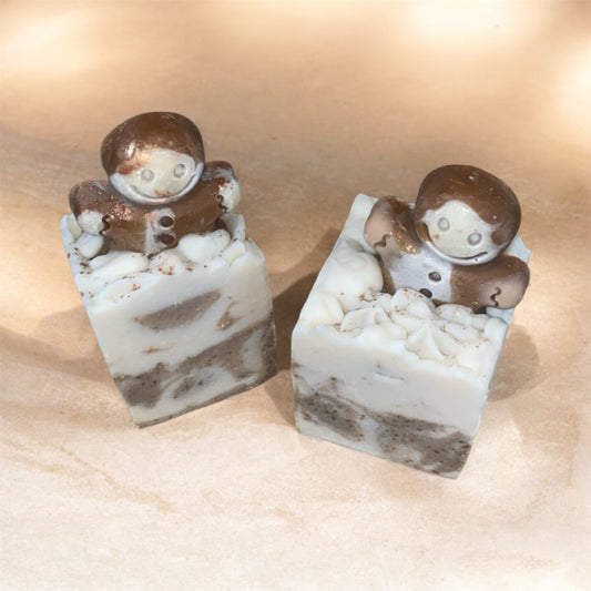 Two small soap with a gingerbread man figures on top with marbled design on a beige background