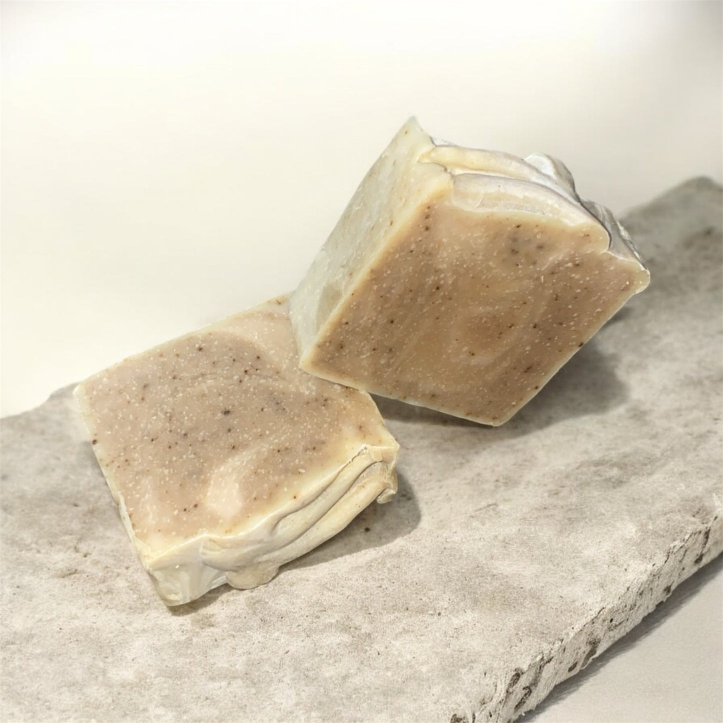 Two bars of soap on a stone surface with a light background