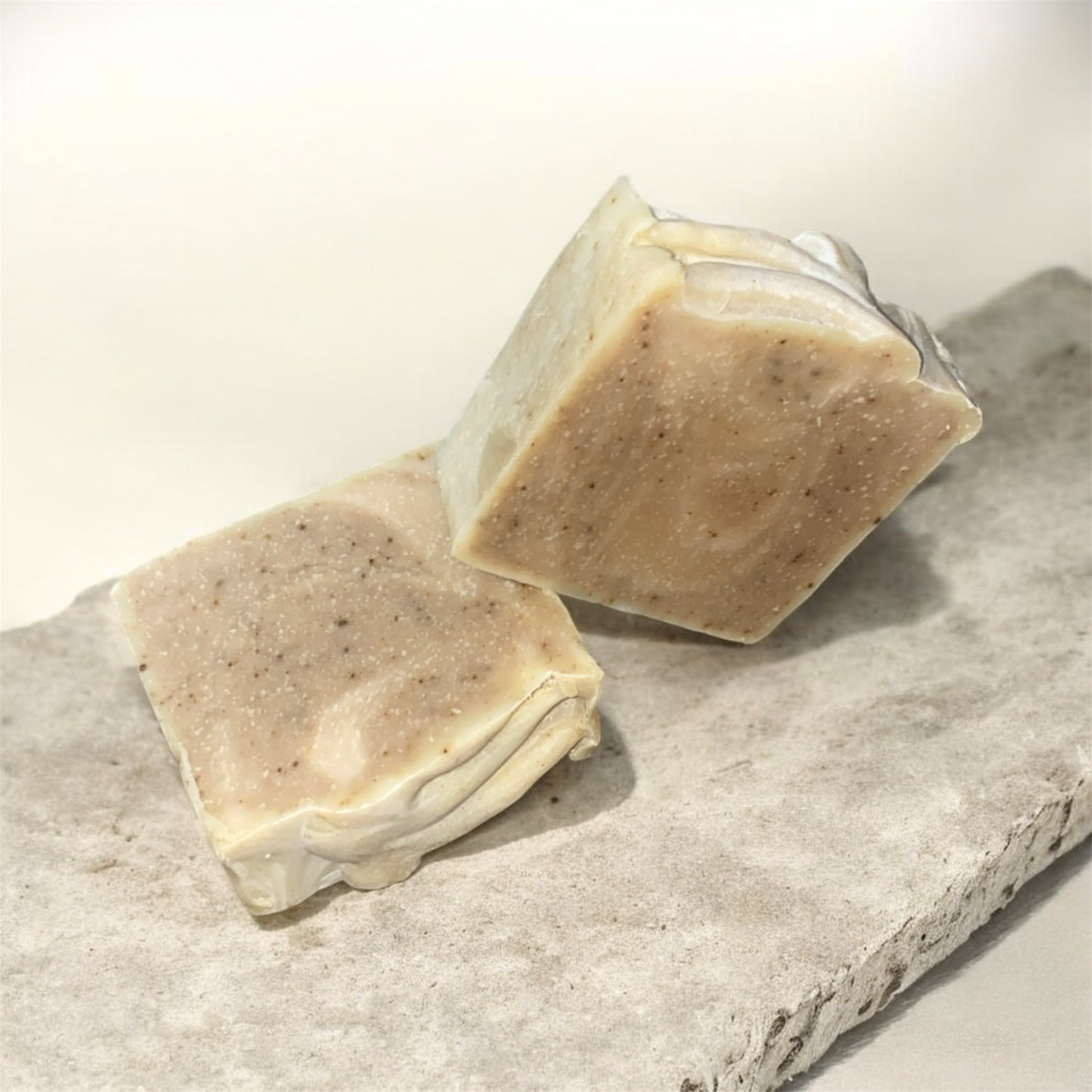 Two bars of soap on a stone surface with a light background