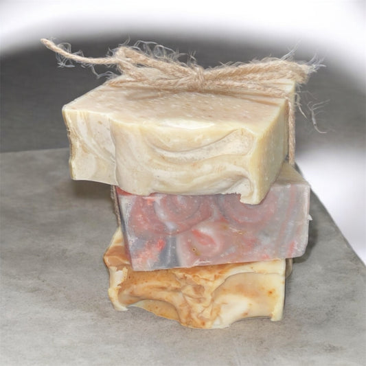 Three bars of soap stacked on a gray surface with a white background