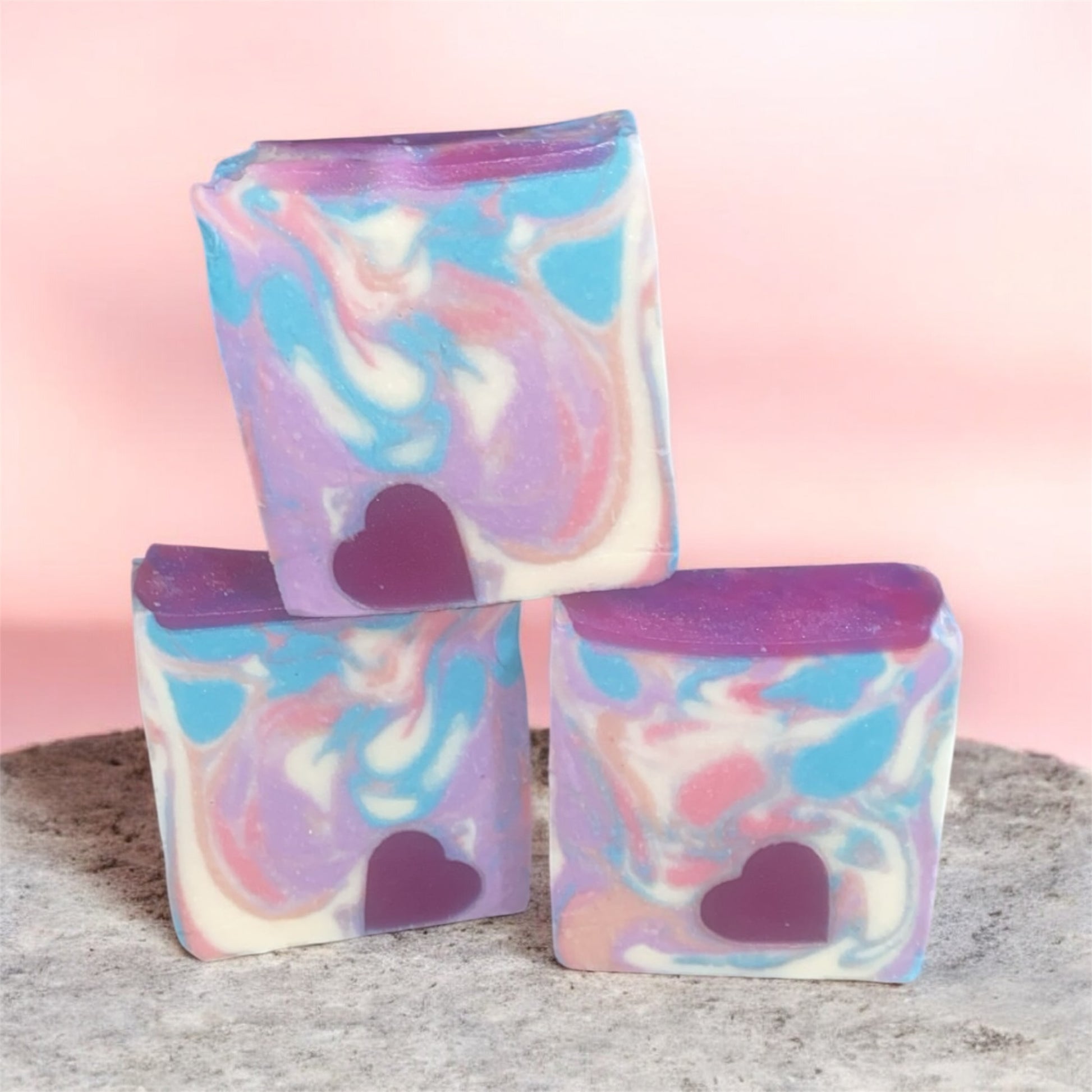 Three colorful soap bars with heart shapes on a neutral background