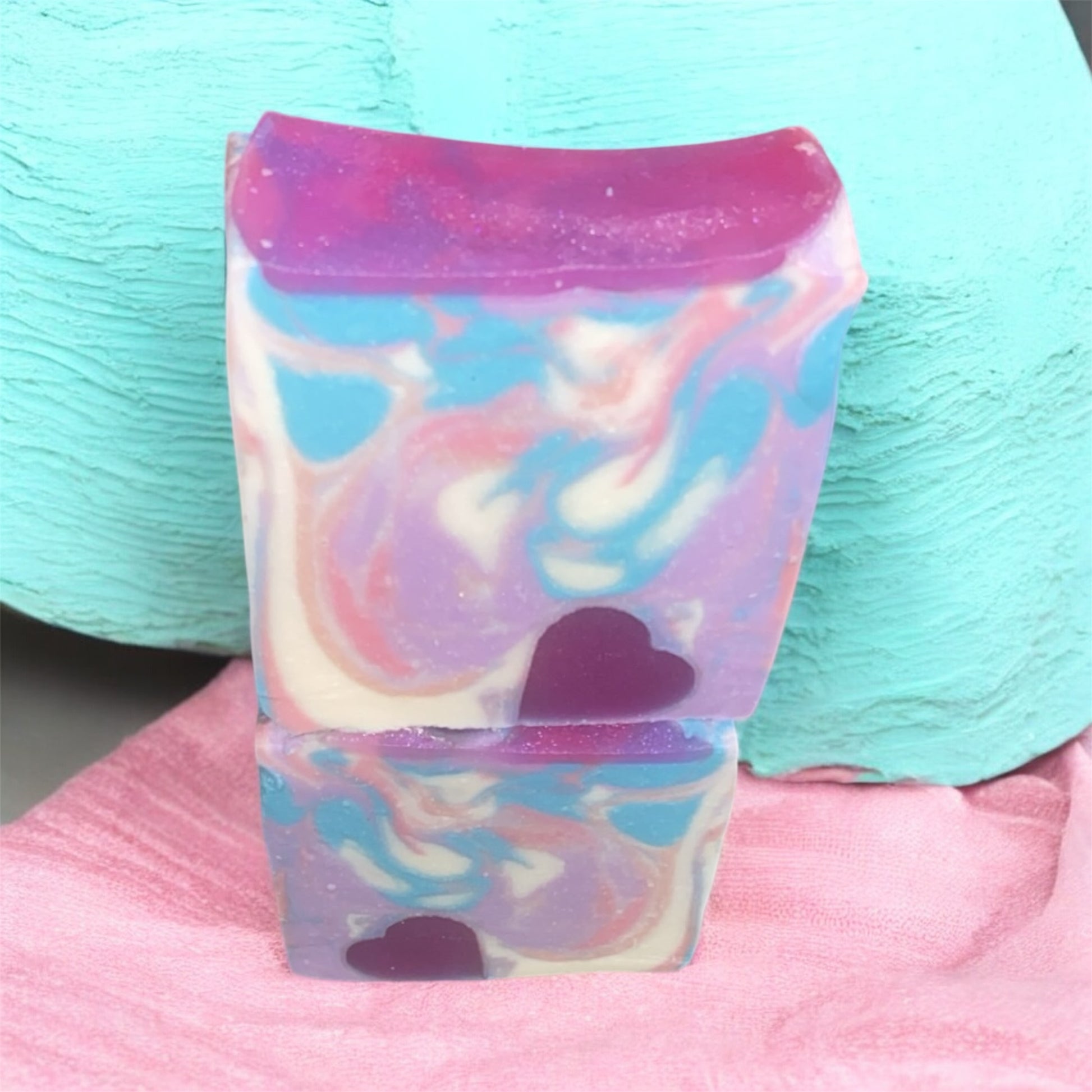 2 soaps with vibrant colors of purple,pink, white and blue with a heart embed with blue and pink background.