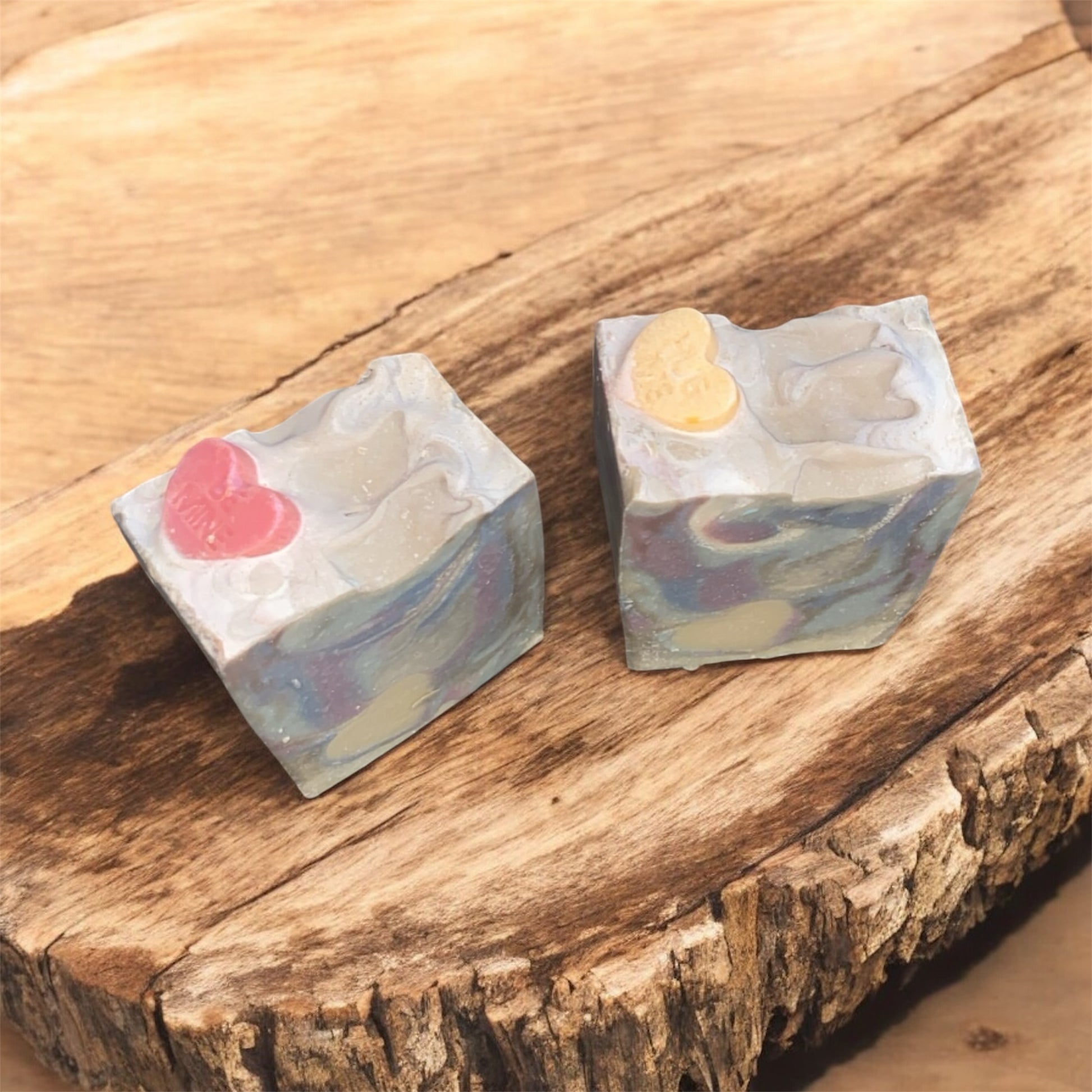 Two soap with vibrant colors sitting on a wooden bench 